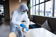 © Wavebreak Media - Health worker in protective clothing spraying disinfectant on table