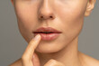 Close up of woman applying moisturizing nourishing balm to her lips with her finger to prevent dryness and chapping in the cold season. Lip protection. 