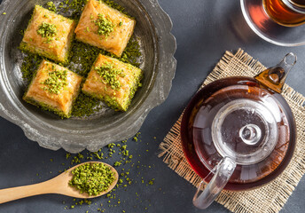 Wall Mural - Traditional turkish dessert pistachio antep baklava with turkish black tea on rustic table,  ramadan or holiday desserts concept