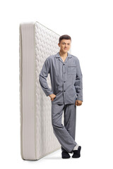 Sticker - Young man in pajamas leaning on a bed mattress and smiling