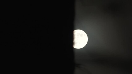 Wall Mural - full moon appears behind dark wall time lapse