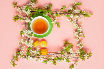 Wall Mural - Cup of tea and a blossom branch of cherries on a picture frame on a grey background. Top view. Copy space