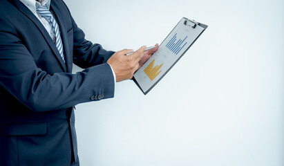 A businessman executive hand in a suit holds a pen pointing to a financial graph