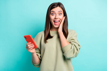 Wall Mural - photo portrait of impressed woman touching cheek face holding phone in one hand isolated on vivid cy
