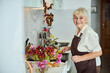 © Viacheslav Yakobchuk - Joyful elderly woman in apron standing in kitchen