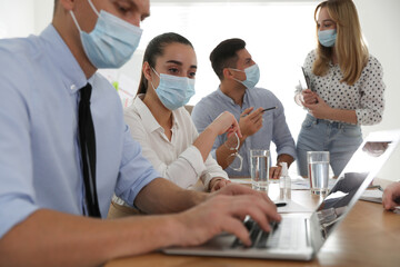 Wall Mural - Group of coworkers with protective masks in office. Business meeting during COVID-19 pandemic