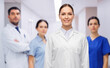 © Syda Productions - medicine, profession and healthcare concept - happy smiling female doctor in white coat over group of colleagues at hospital on background