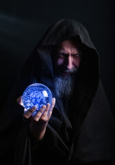 Wall Mural - bearded man in a hood with a glowing magic ball