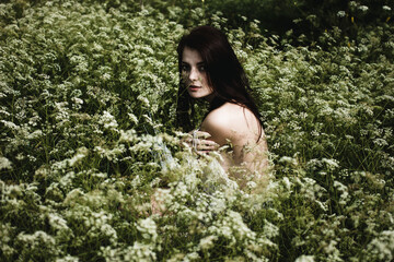 Young woman with black hair and naked back among wildflowers