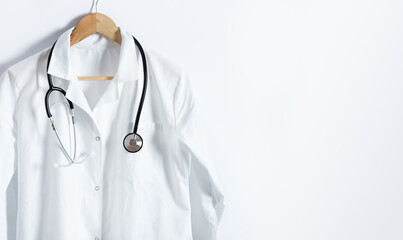 Doctor's white coat with stethoscope on hanger over white background with copy space.