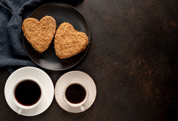 Two coffee and two heart-shaped cakes on a stone background. breakfast for valentine's day with copy space for your text