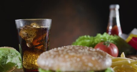 Wall Mural - Camera pans slowly across the fast food dining table - cola and potato fries, stopping in front of a juicy hamburger. Blackmagic Pocket Cinema Camera 6K.