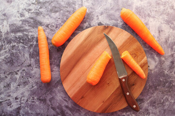 fresh carrots on chopping board on table 