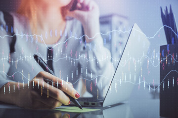 Double exposure of woman hands typing on computer and financial graph hologram drawing. Stock market analysis concept.