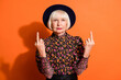 Photo portrait of bad rude granny showing fucking sign gesture in black hat isolated on vibrant orange background copyspace