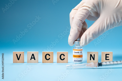 Promising Covid-19 Vaccine concept. Hand of a researcher take a 2019-nCov vaccine vial with wooden alphabet letters \