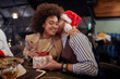 © luckybusiness - young couple having fun, smiling, laughing, eating breakfast in bed,  wearing santa hats, christmas, present