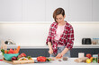 © Svyatoslav Lypynskyy - Cooking at home for loving family. Pretty young woman cutting ingredients on table cooking a lunch or dinner standing in the kitchen. Healthy food living. Healthy lifestyle.