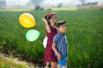 Happy children with balloons in agricultural field