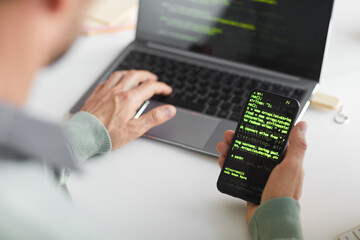 Wall Mural - close-up of man installing new software system on his mobile phone from laptop