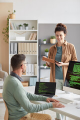 Wall Mural - young woman discussing with her colleague new computer program on computer during working day at off