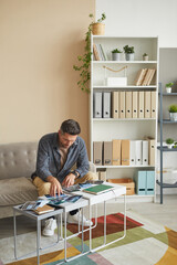 Wall Mural - mature photographer sitting on sofa looking at photos with landscapes he choosing his best work