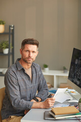 Wall Mural - portrait of mature photographer looking at camera while working with photos at his workplace at offi
