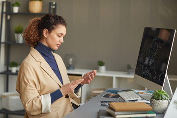 Wall Mural - serious female designer working with photos at her workplace with computer monitor on it at office