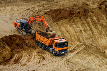 excavator moving earth and unloading into a dumper truck