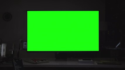 Dolly in of desktop computer with green screen. Evening in the office or home office, big dark room with several devices. Chroma key. Put your own images or videos. Track with perspective corner pin.