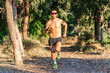 © Javier De La Torre/ADDICTIVE STOCK - Full body of serious active sportsman in sunglasses running fast on path while training in green forest in summer day