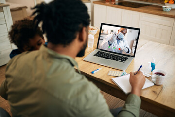 Wall Mural - Black pediatrician having video call with a father who is taking care of his ill son at home.