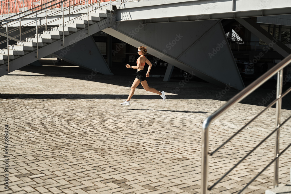Running Fast Side View Side view of determined female athlete running fast during outdoor ...