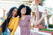 © Sergio Victor Vega/ADDICTIVE STOCK - Smiling black woman with braids hugging cheerful African American female friend with curly hair and taking selfie together while standing on promenade in summer