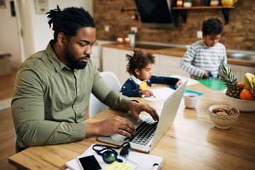 Wall Mural - African American single father working on laptop at home.