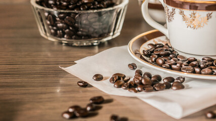 Cup of coffee and coffee beans on white paper on old wooden background