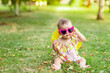 © Any Grant - a baby with glasses and a hat on a green lawn in summer in yellow clothes