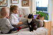 © Irina Ozhigova/Stocksy - Kids with a cat are sitting on the couch