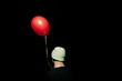 © Vladimir Tsarkov/Stocksy - anonymous person in cap with red balloon in the dark