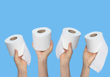 Hands holding toilet paper rolls on blue background