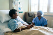 © FS Productions/Blend Images - Black nurse talking to boy in hospital bed