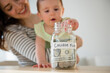 © JGI/Jamie Grill/Blend Images - Mother and baby putting money in college fund