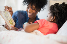 Mother And Daughter Reading In Bed