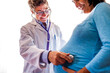 © Adam Hester/Blend Images - Doctor listening to woman√ïs pregnant belly