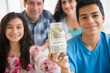 © JGI/Jamie Grill/Blend Images - Hispanic family holding full vacation savings jar