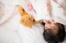 Filipino Girl Playing With Teddy Bear In Bed