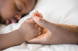 © JGI/Jamie Grill/Blend Images - Close up of Black mother holding hand of sleeping baby
