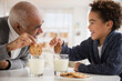 © JGI/Jamie Grill/Blend Images - Mixed race grandfather and grandson eating cookies and milk