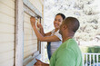 © Annika Erickson/Blend Images - Couple attaching frame to outside of house