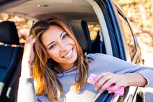 Mixed Race Woman Holding Cell Phone In Car